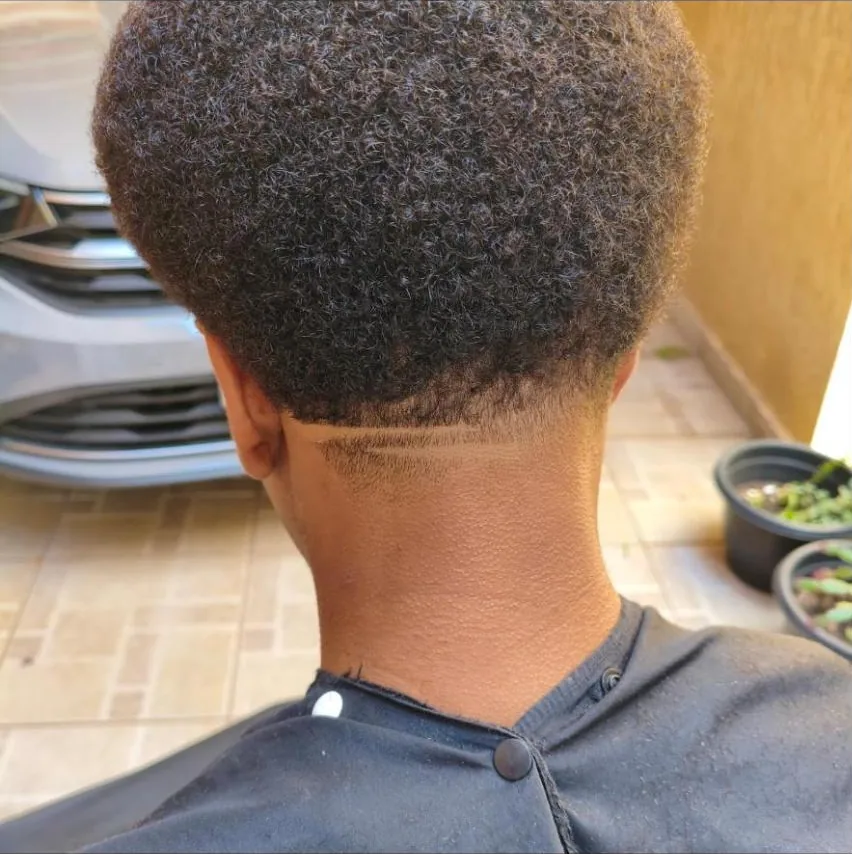 Nuca de um cliente com cabelo afro e risca desenhada no degradê